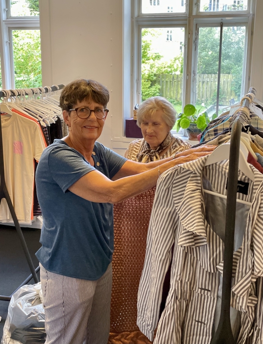 Frivillig som står ved tøjet i genbrugsbutikken